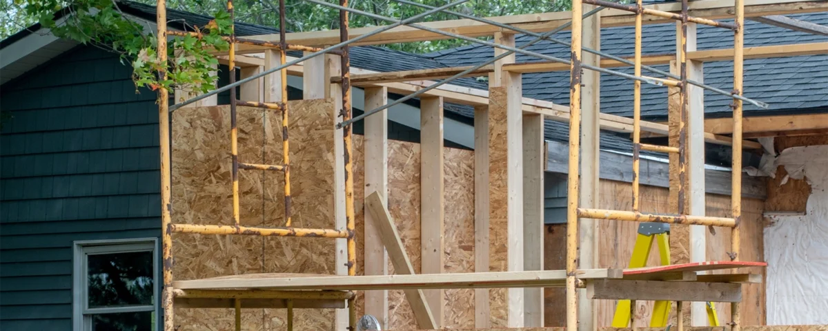 House extension framing in progress with timber wall studs and roof trusses adding living space.